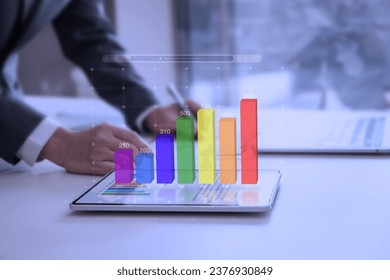 Colorful augmented reality bar graph floating above the tablet screen surface showing periodic business performance or financial information for investment - Powered by Shutterstock