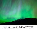 Colorful Aurora Borealis rays raining down on North Cascades National Park mountain peak