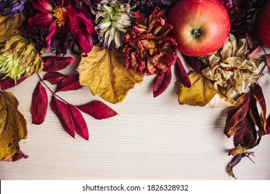 Colorful autumn flatlay. Wilted flowers (chrysanthemum, golden-daisy), dried read and yellow leaves and red apples on the light wooden background. Seasonal fall concept. Top view, copy space. - Powered by Shutterstock