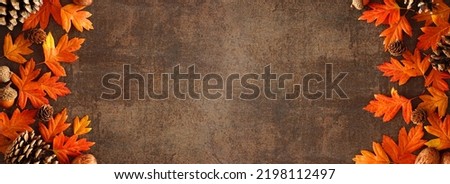 Colorful autumn leaves, nuts and pine cones. Double border over a rustic dark banner background. Top down view with copy space.