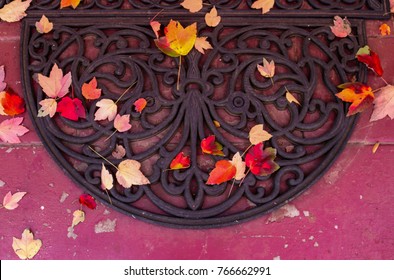 Colorful autumn maple leaves on door mat and porch