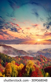 Colorful autumn sunset in the foggy mountains.