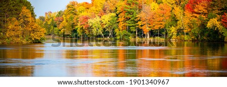 Colorful autumn trees reflecting off of the Wisconsin River in Merrill, Wisconsin, panorama