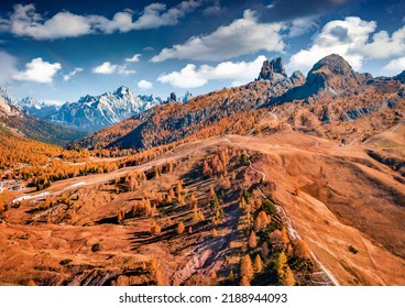 Colorful autumn view from flying drone top of Falzarego pass. Majestic autumn scene of Dolomite Alps with Torre Grande Cima Ovest peak on background, Italy, Europe. Traveling concept background.