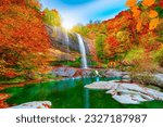 Colorful autumn waterfall landscape. Autumn colors in beautiful nature. Forest view in fall season.