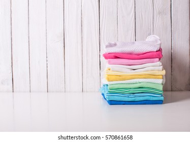 Colorful Baby Clothes Of Folded Pile On A White Background