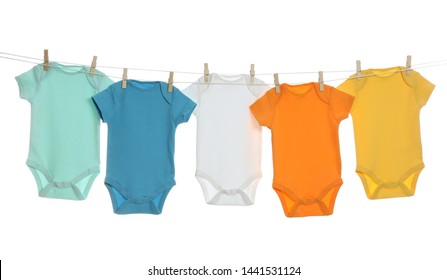 Colorful baby onesies hanging on clothes line against white background. Laundry day