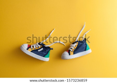 Colorful baby shoes on bright yellow background in child's room