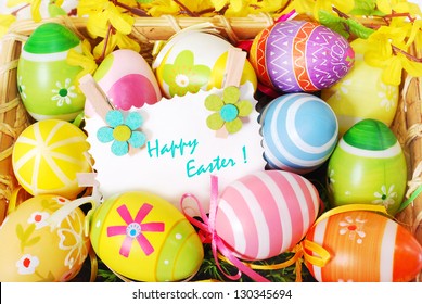 colorful background with easter painted eggs and greeting card  in wicker basket