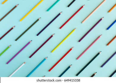 Colorful background with many crayons pastels lined up on azure aquamarine - Top view flat lay