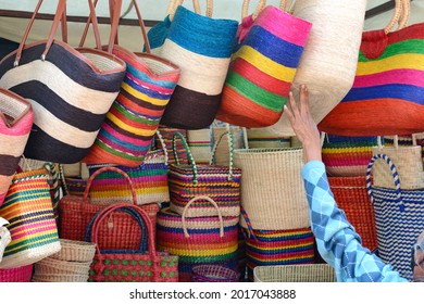 Colorful bags woven from palm fibers in a handicraft market.