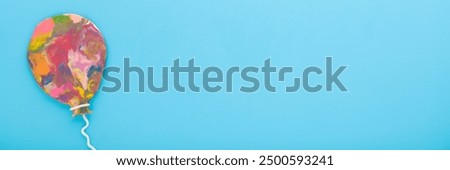 Colorful balloon shape created from modeling clay on light blue table background. Pastel color. Closeup. Wide banner. Empty place for lovely text, quote or sayings. Top view.