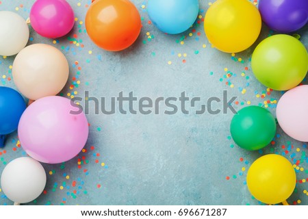 Colorful balloons and confetti on blue table top view. Festive or party background. Flat lay style. Copy space for text. Birthday greeting card.
