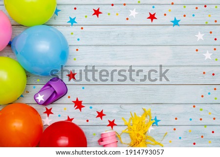 Colorful balloons and confetti on wooden table top view. Festive or party background. Flat lay style. Birthday greeting card. Carnival.