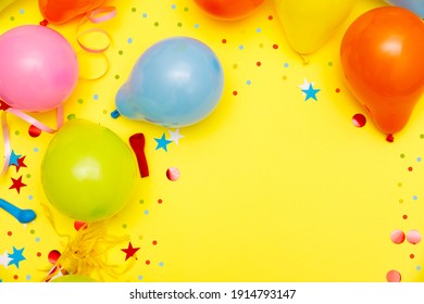 Colorful Balloons And Confetti On Yellow Table Top View. Festive Or Party Background. Flat Lay Style. Birthday Greeting Card. Carnival.