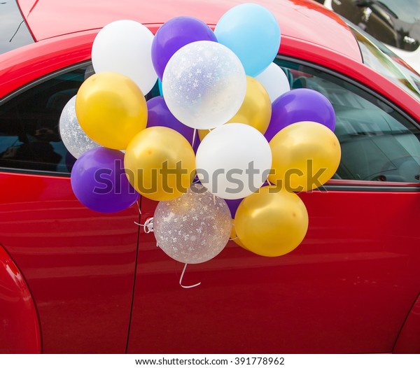 \
a lot of colorful balloons with helium for a\
holiday in the red car