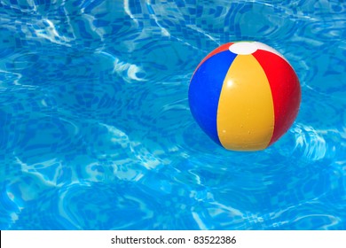 A colorful beach ball floating in a blue swimming pool