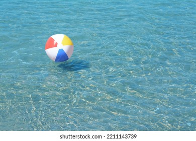 Colorful beach ball floating in sea on sunny day, space for text - Powered by Shutterstock