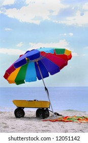 Colorful Beach Umbrella On Beach With Towel And Wagon