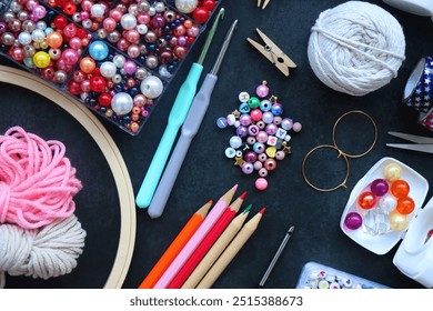 Colorful beads, coloring pencils, glitter, needles, string, hoop, tape and scissors on dark background. Various colorful craft supplies. Flat lay. - Powered by Shutterstock