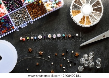 Colorful beads and various jewelry making supplies on dark background. Letter beads spelling I heart DIY. Top view.