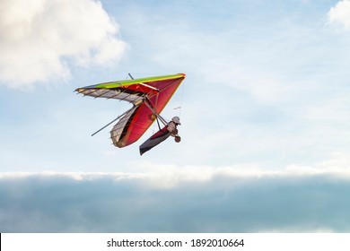 Colorful beginner hang glider wing silhouette with blue sky on the background. Learning to fly