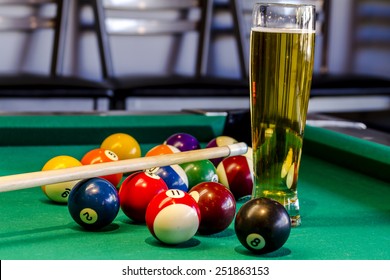 Colorful Billiard Balls And Pool Stick Sitting On Pool Table With Glass Of Beer