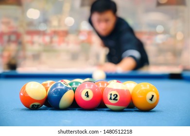 The Colorful Billiard Or Pool Balls For Snooker Game Are On Blue Billiard Table For Starting The Match With Blur Image Of Player.
