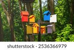 A colorful birdhouse with a black pole holding it up. The birdhouses are of different colors and sizes