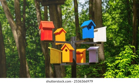 A colorful birdhouse with a black pole holding it up. The birdhouses are of different colors and sizes - Powered by Shutterstock