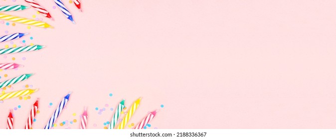 Colorful Birthday Cake Candles With Candy Sprinkles. Top Down View Banner With Corner Border On A Pink Background. Copy Space.