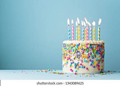 Colorful birthday cake with sprinkles and ten candles on a blue background with copyspace - Shutterstock ID 1343089625