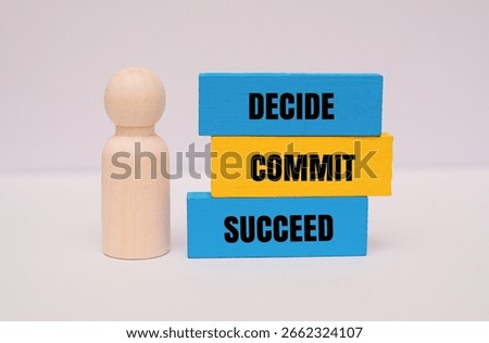 Colorful block with text DECIDE, COMMIT, SUCCEED next to wooden figurine