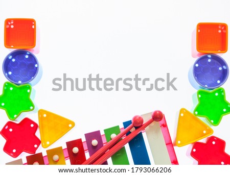 Colorful blocks for sorter box with children xylophone musical instrument, flat lay frame with blank space, a white background