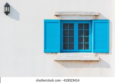 Colorful Blue Window And Detail Of House Exterior On White Wall.