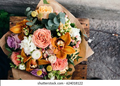 Colorful  Bouquet Of Different Fresh Flowers Against Brick Wall. Bunch Of Orchids, Roses, Freesia And Eucalyptus Leaves. Rustic Flower Background. Top View