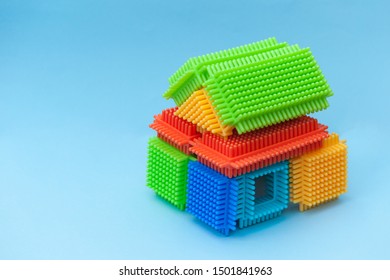 Colorful Bristle Blocks In Shape Of House  On Blue Background. Copy Space,