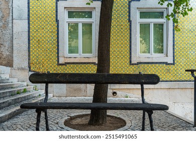 Colorful building with traditional Portuguese tile azulejo on the wall and bench on medieval street in old town of Lisbon city, Portugal. Cobblestone alley in Lisboa. Popular touristic destination - Powered by Shutterstock