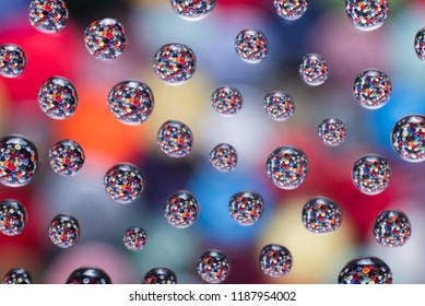 Colorful buttons in water drops. The buttons are blurry in the background. - Shutterstock ID 1187954002