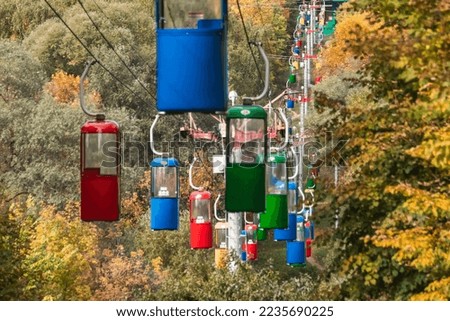 Colorful cableway cabins in autumn greenery in Kharkiv city recreation park
