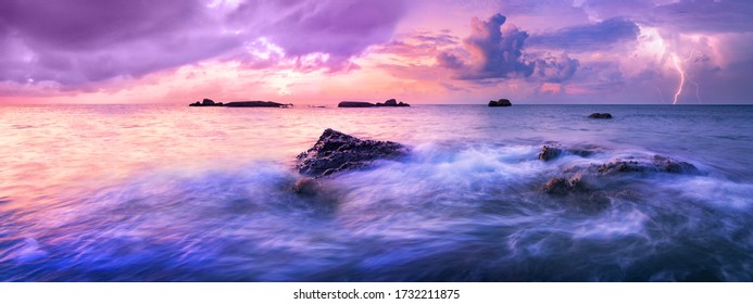 Colorful calm sea during sunset. A storm is approaching over the horizon. Colorful dark clouds in the air, electric discharges herald the coming storm.