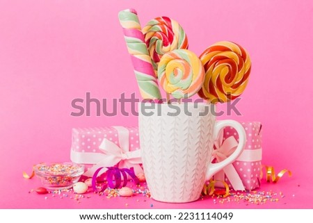 Colorful candies in cup on table on light background background. Large swirled lollipops. Creative concept of a jar full of delicious sweets from the candy store.