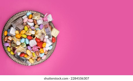Colorful candies, top view image of colorful candies in vintage copper bowl. Isolated pink background. Copy space text area. Ramadan Kareem called Şeker Bayramı in Turkish. Greetings card concept idea