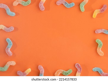 Colorful Candy Worm Pattern. Halloween Trick Or Treat Minimal Copy Space On Orange Background.