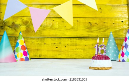 Colorful card happy birthday with festive decorations with cake and burning candles. Copy space. Beautiful happy birthday background on the background of yellow boards with a number of candles 16