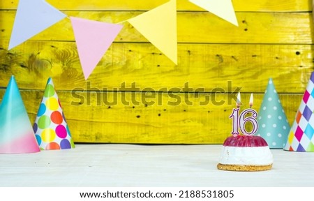Colorful card happy birthday with festive decorations with cake and burning candles. Copy space. Beautiful happy birthday background on the background of yellow boards with a number of candles 16