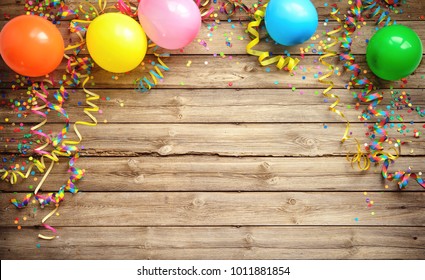 Colorful carnival or party frame of balloons, streamers and confetti on rustic wood planks with copy space