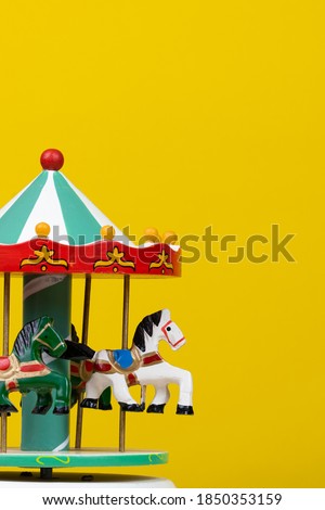 colorful carousel toy in yellow background. Vertical