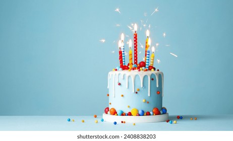 Colorful celebration birthday cake with colorful birthday candles and sparklers against a blue background