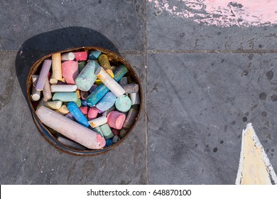 Colorful Chalk In Rusty Box On Side Walk For Children Play And Creation Drawing On Street Playground.